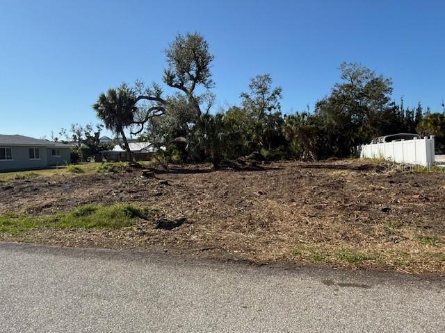 A cleared, vacant residential lot features scattered trees under a clear blue sky — 9161 PINE COVE DRIVE, ENGLEWOOD, FL