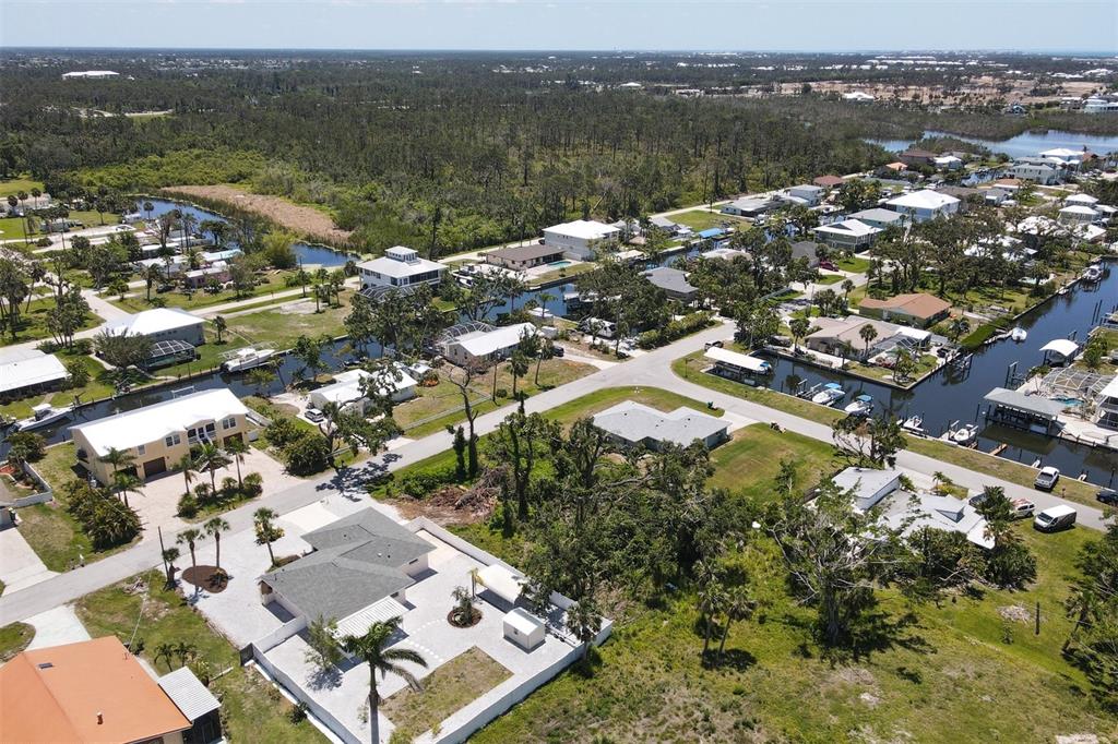 An aerial view shows a residential neighborhood with houses, canals, and surrounding wooded areas — 9161 PINE COVE DRIVE, ENGLEWOOD, FL