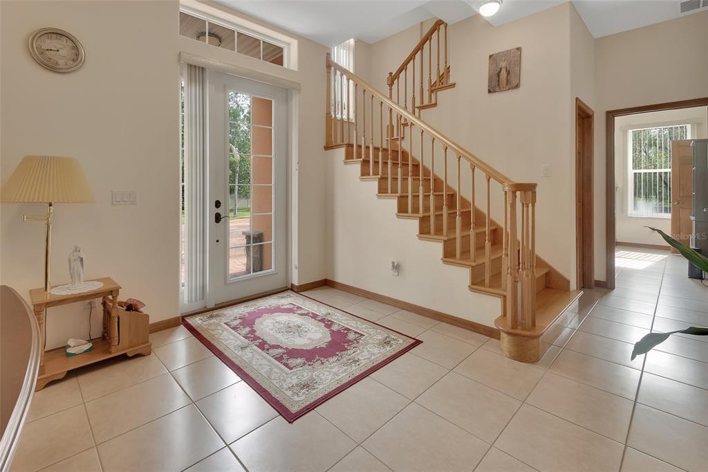 A foyer features tile flooring, a wooden staircase, and a glass-paneled front door — 443 JUNIPER LANE, ORMOND BEACH, FL