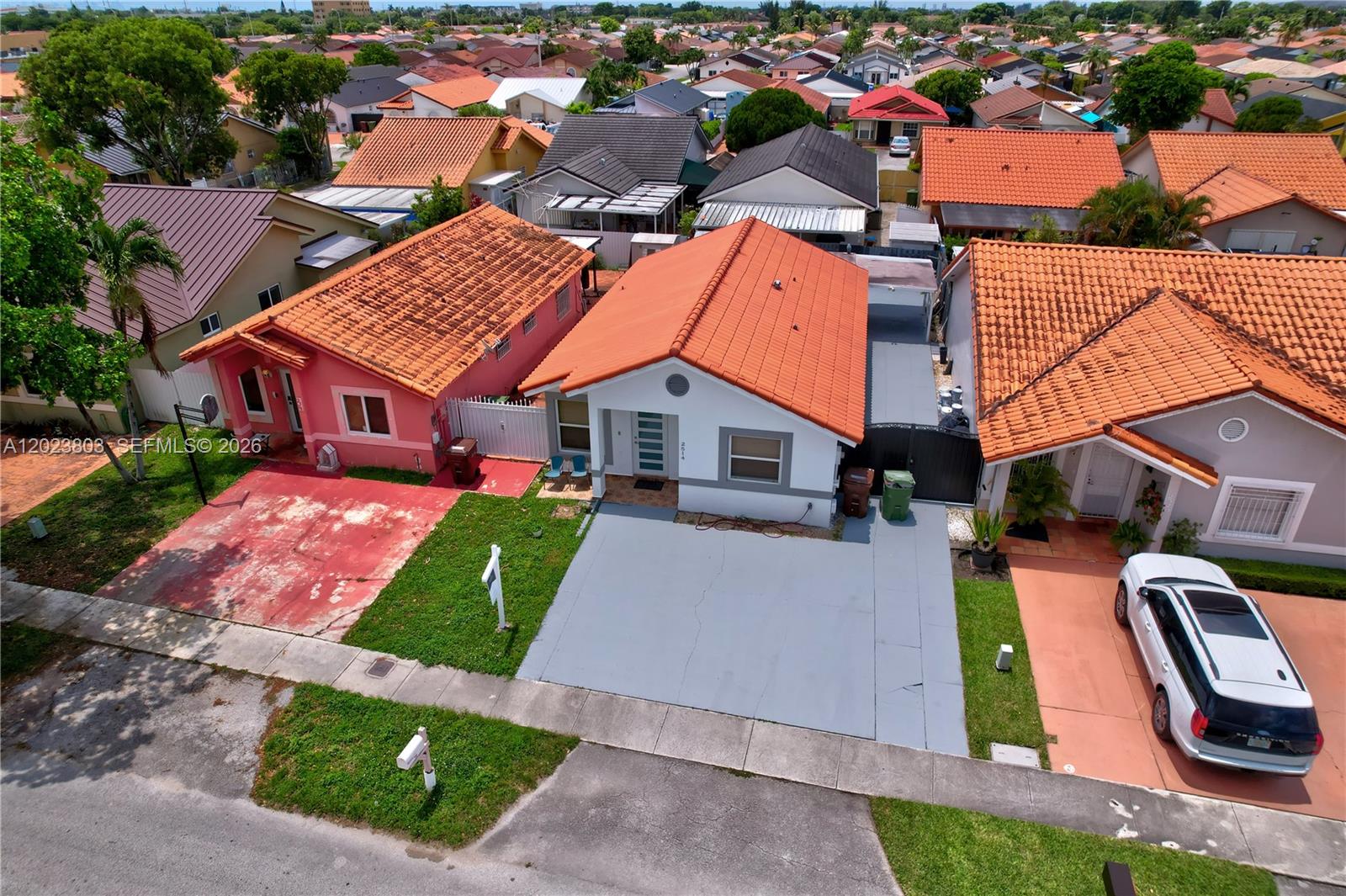 An aerial view shows three suburban houses with orange tile roofs and paved driveways — 2514 W 74th St, Hialeah FL 33016, HIALEAH, FL
