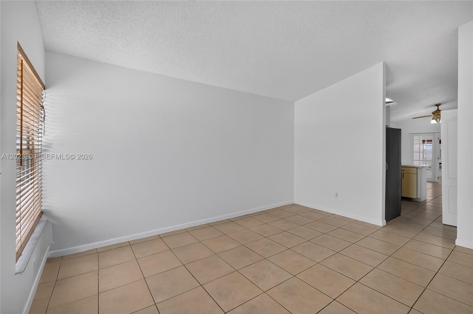 An empty room features white walls, beige tile flooring, and a window with blinds — 2514 W 74th St, Hialeah FL 33016, HIALEAH, FL