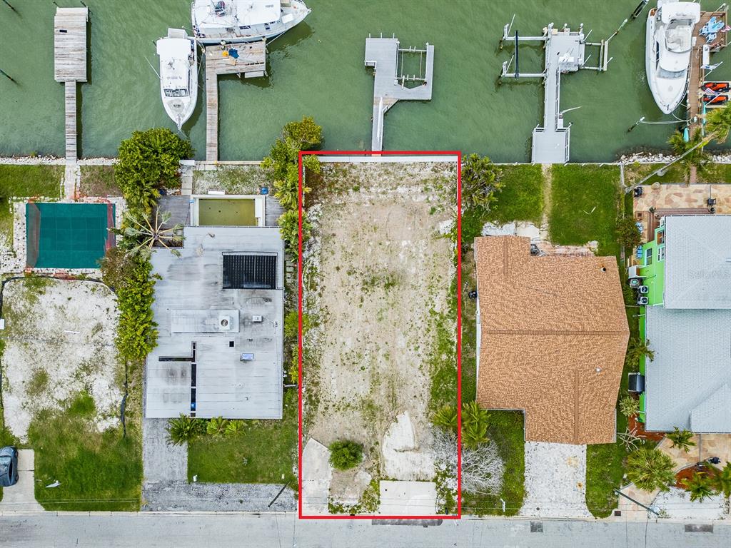 An aerial view shows a vacant rectangular waterfront lot situated between two existing residential properties — 813 BAY POINT DRIVE, MADEIRA BEACH, FL