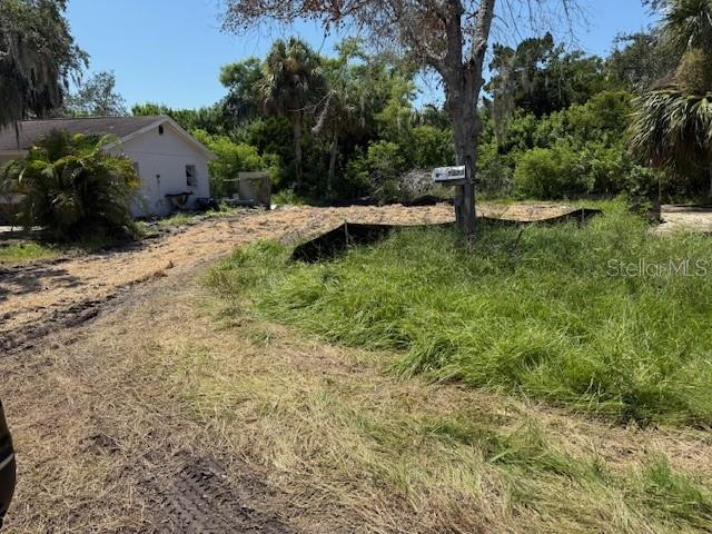 A view of a cleared dirt lot next to a white house and trees — 7323 JANCZLIK DRIVE, NEW PORT RICHEY, FL