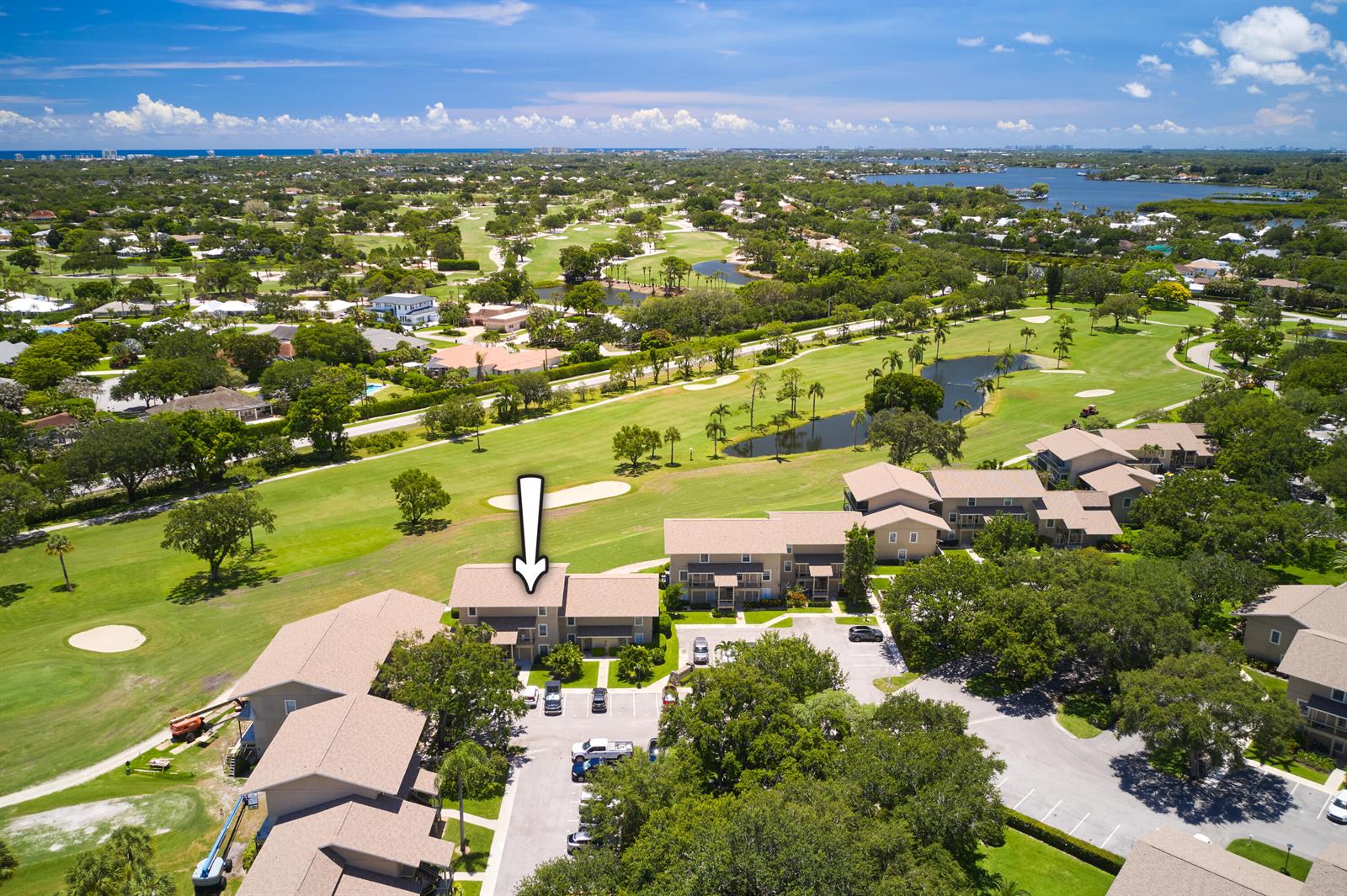 An aerial view shows a multi-story residential building with a white arrow pointing toward it — 18439 SE Wood Haven Lane # M, Jupiter FL 33469, JUPITER, FL