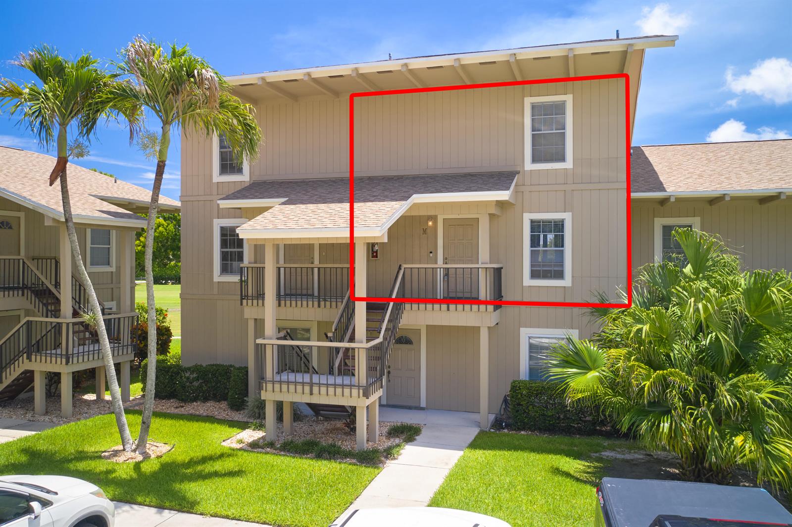 An exterior view of a two-story apartment building with a highlighted upper-level unit — 18439 SE Wood Haven Lane # M, Jupiter FL 33469, JUPITER, FL