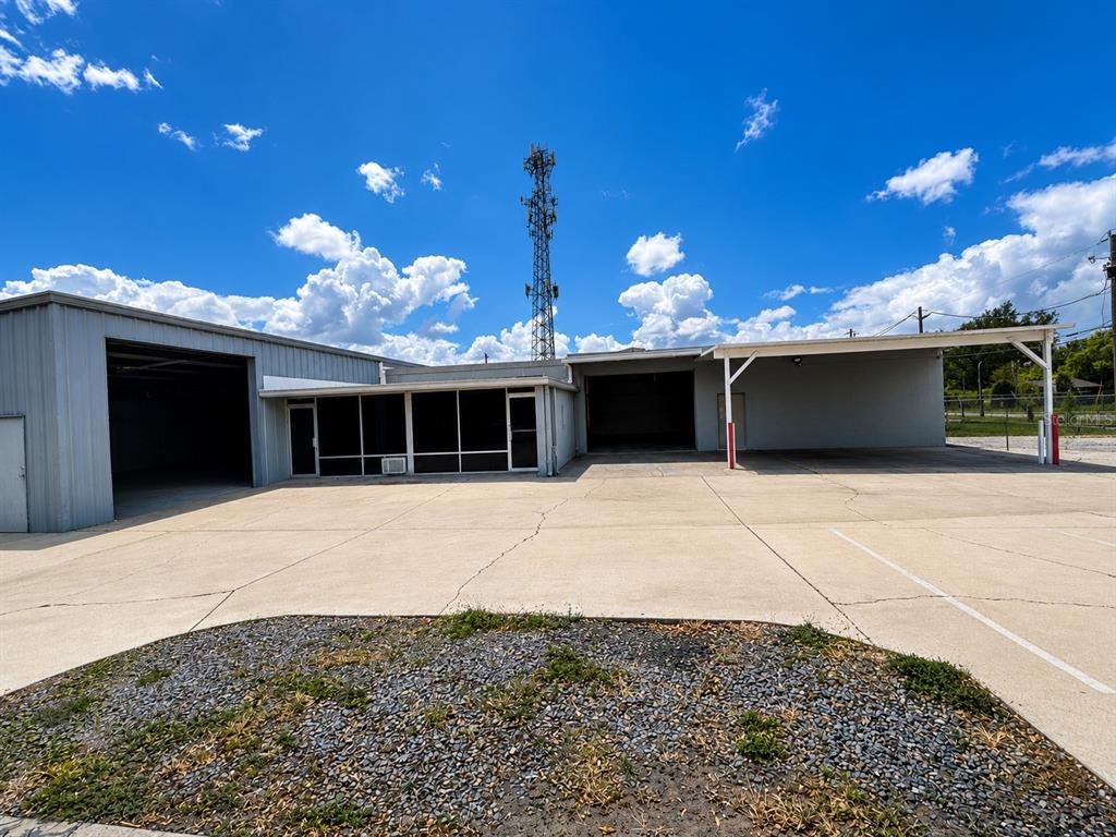 An exterior view of a commercial building with a large concrete parking area and tower — 5909 ANNO AVENUE, ORLANDO, FL