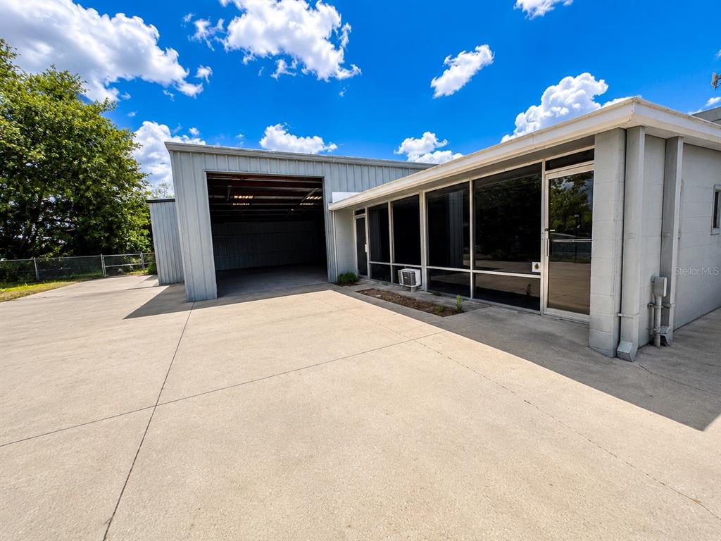 A commercial building features a large open garage bay and an adjacent office area — 5909 ANNO AVENUE, ORLANDO, FL