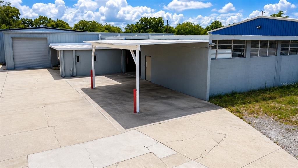 An exterior view shows a gray industrial building with a covered parking area and concrete lot — 5909 ANNO AVENUE, ORLANDO, FL