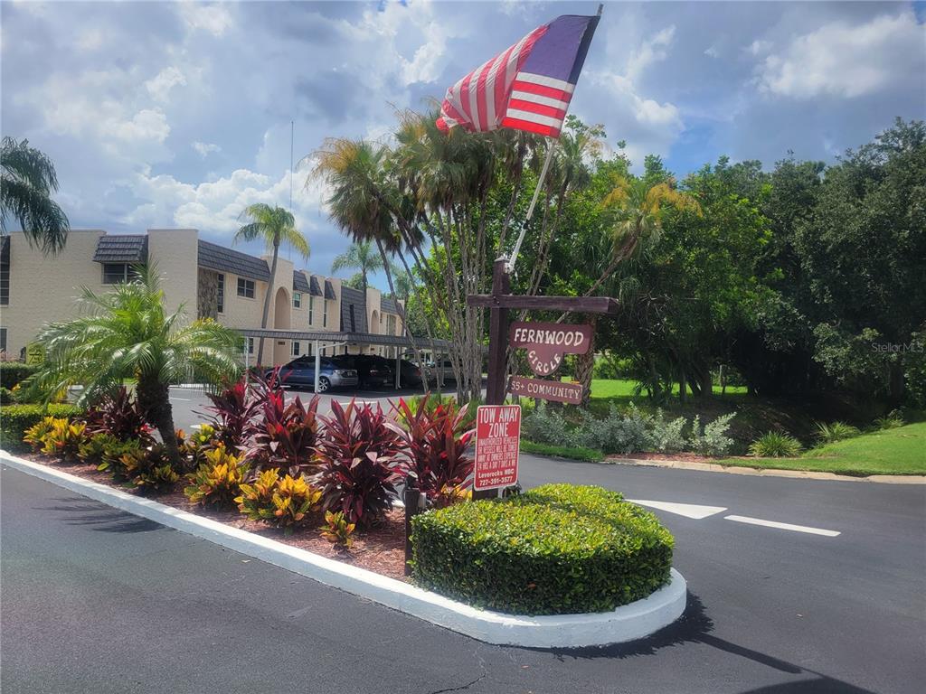 An entrance sign for a 55+ community stands near a parking area with palm trees — 114 FERNWOOD CIRCLE UNIT 114, SEMINOLE, FL