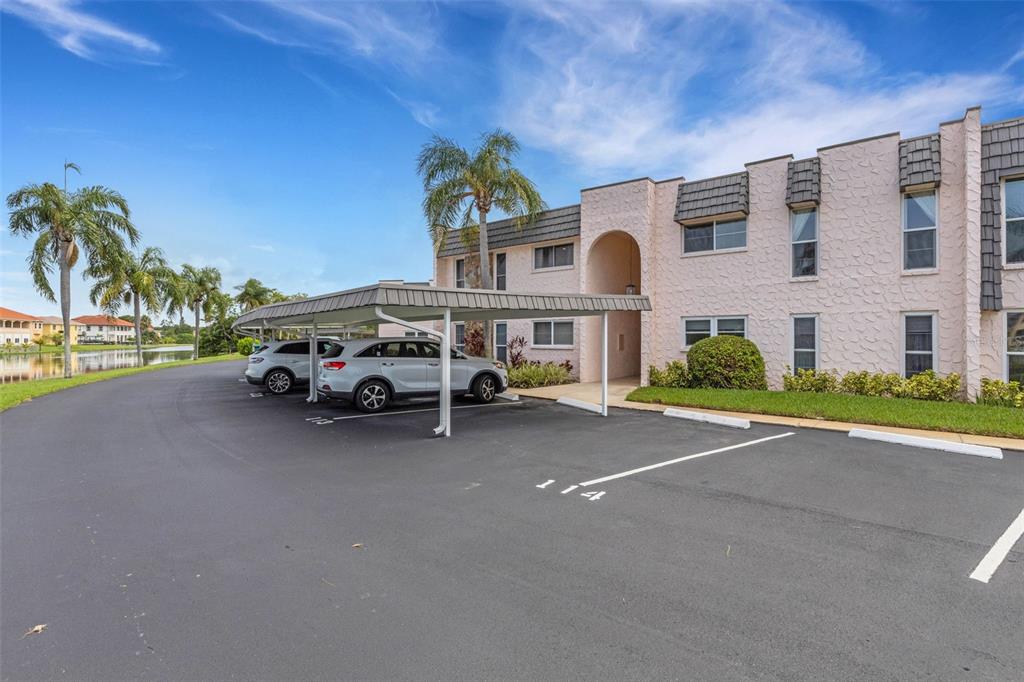 A two-story apartment building with a covered parking area and a nearby lake — 114 FERNWOOD CIRCLE UNIT 114, SEMINOLE, FL