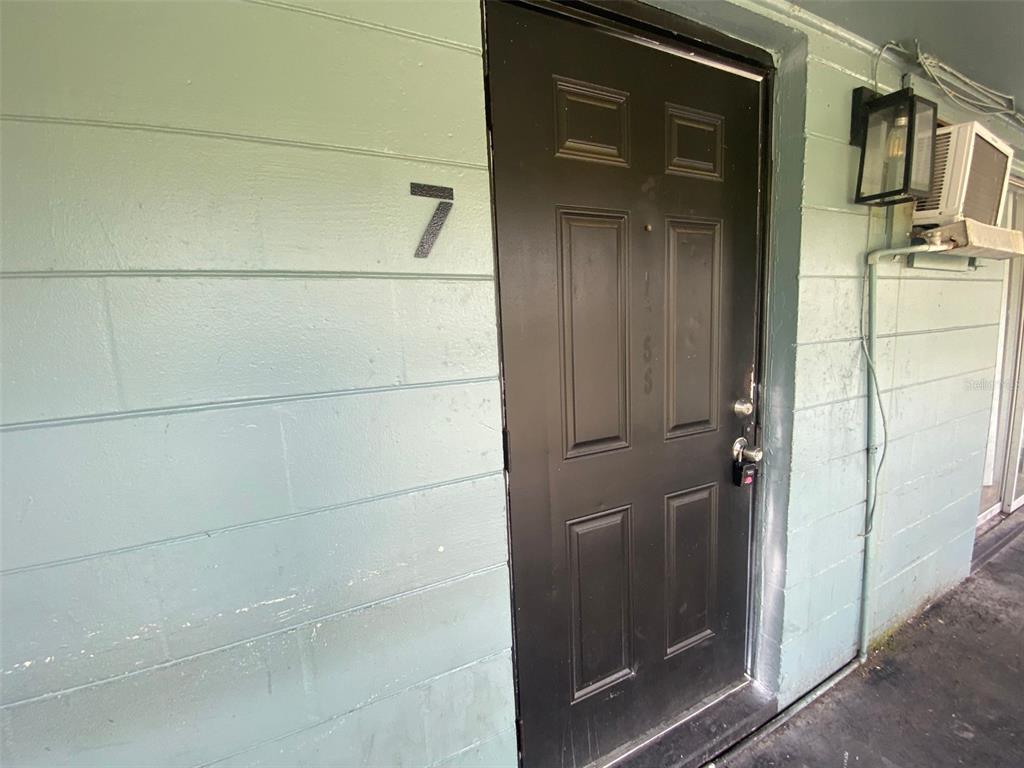 A black front door with the number seven on a light green exterior wall — 1341 WEST POINT DRIVE UNIT 07, COCOA, FL