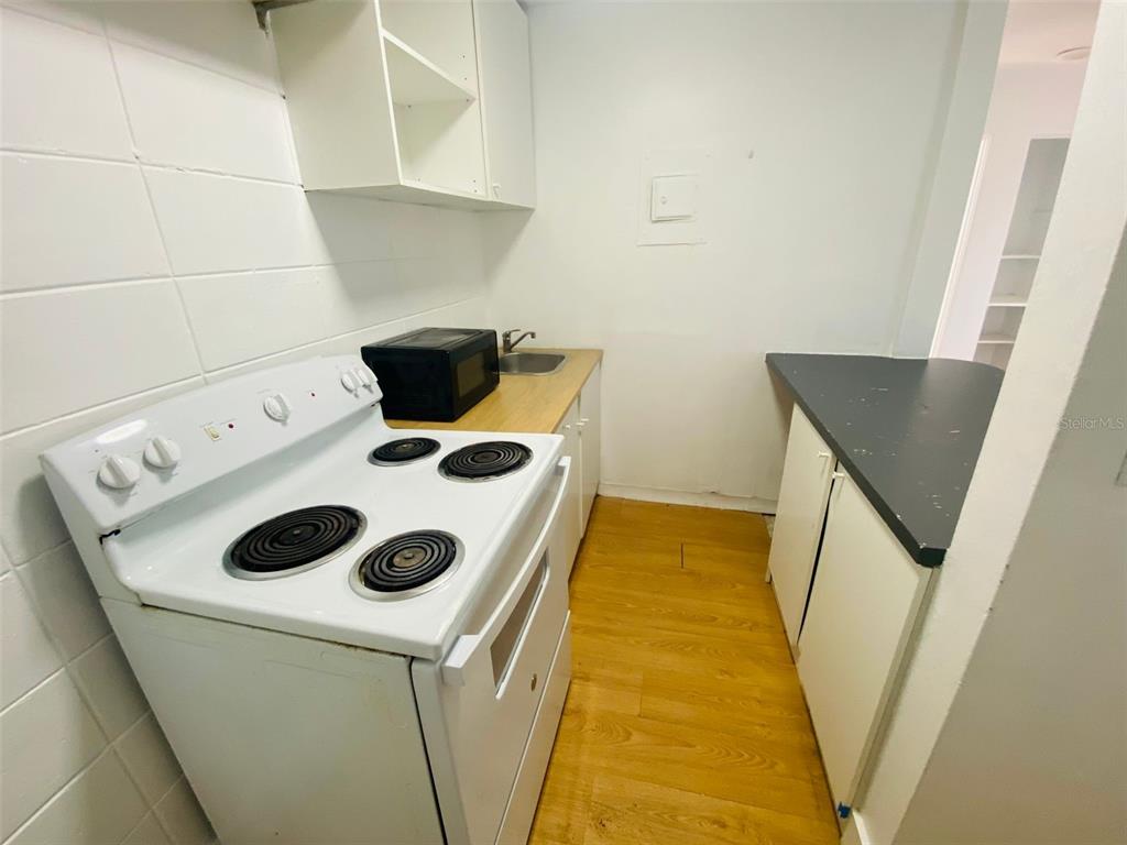 A small kitchen features a white electric stove, wooden cabinets, and a dark countertop — 1341 WEST POINT DRIVE UNIT 07, COCOA, FL