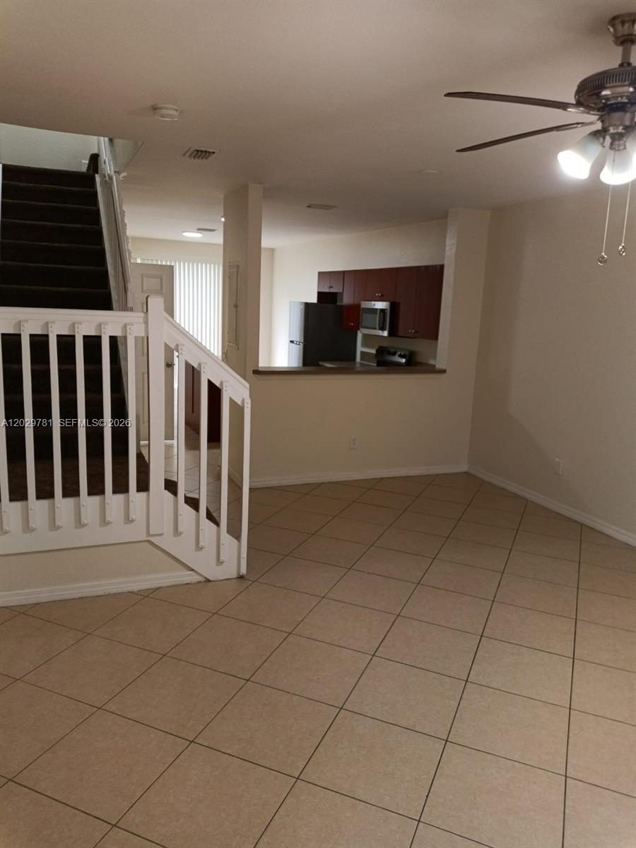 A living area with tile floors, a staircase, and a view into the kitchen — 1936 Alamanda Way # 1, Riviera Beach FL 33404, RIVIERA BEACH, FL