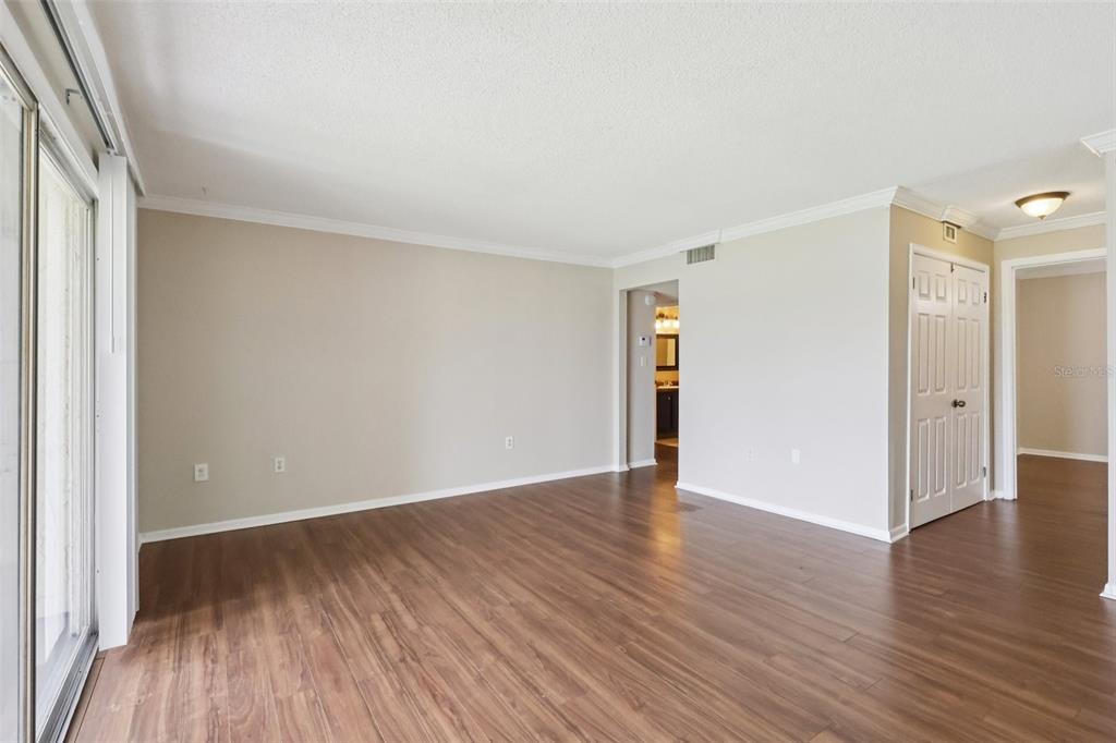 An empty living room with light-colored walls, wood-look flooring, and a sliding glass door — 534 ORANGE DRIVE UNIT 27, ALTAMONTE SPRINGS, FL