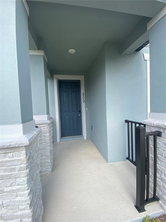 A covered entryway features a dark blue door, light blue walls, and stone-accented pillars — 4512 HOMESTEAD TRAIL, ST CLOUD, FL