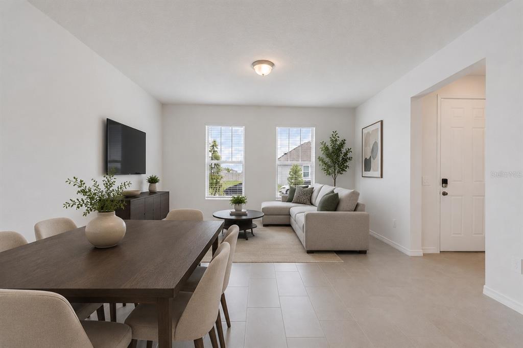 An open-concept living and dining area features light tile floors, neutral furniture, and two windows — 4512 HOMESTEAD TRAIL, ST CLOUD, FL