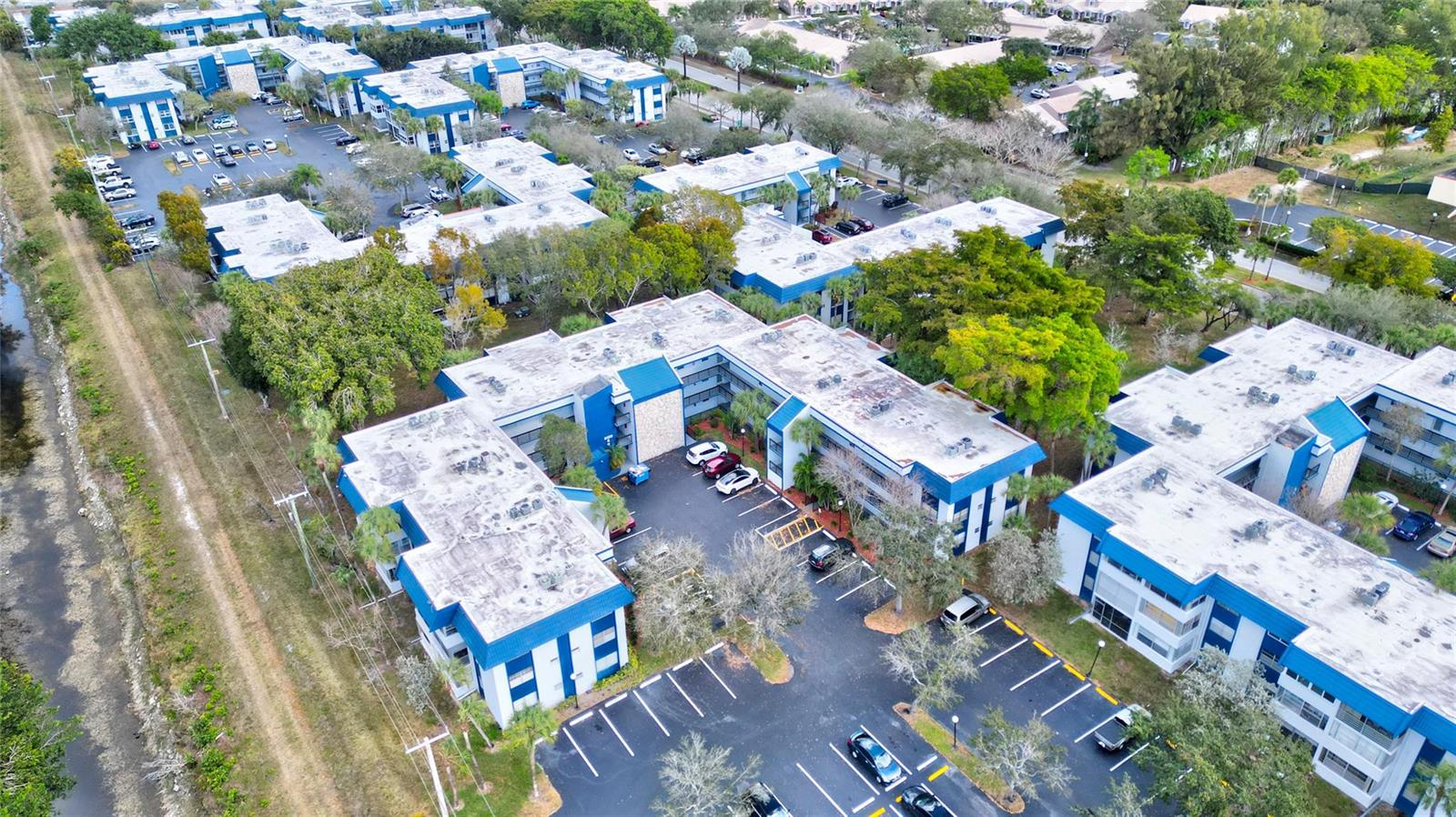 An aerial view shows multiple multi-story apartment buildings with flat roofs and parking lots — 3150 Holiday Springs Boulevard # 311, Margate FL 33063, MARGATE, FL