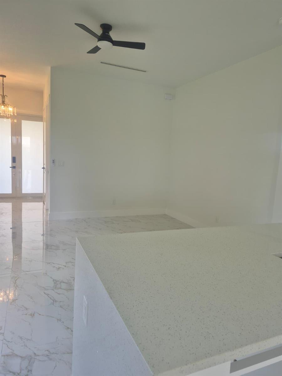 A bright room features white walls, a ceiling fan, and light-colored marble-patterned tile flooring — 546 Pachman Circle, Lehigh Acres FL 33974, LEHIGH ACRES, FL
