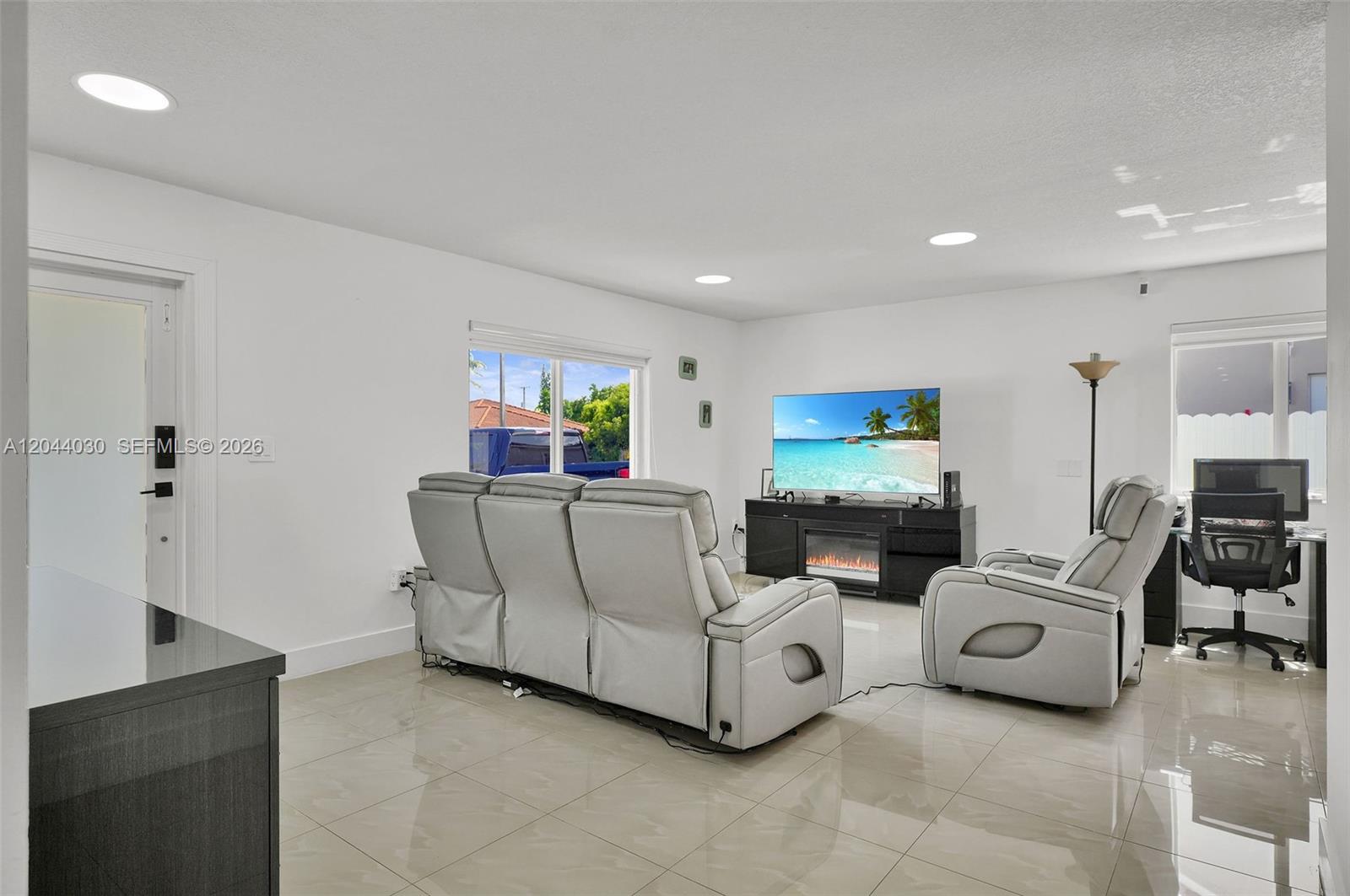 A living room features light tile floors, white walls, a sofa, a recliner, and a television — 12551 SW 223 ST, Miami FL 33170, MIAMI, FL