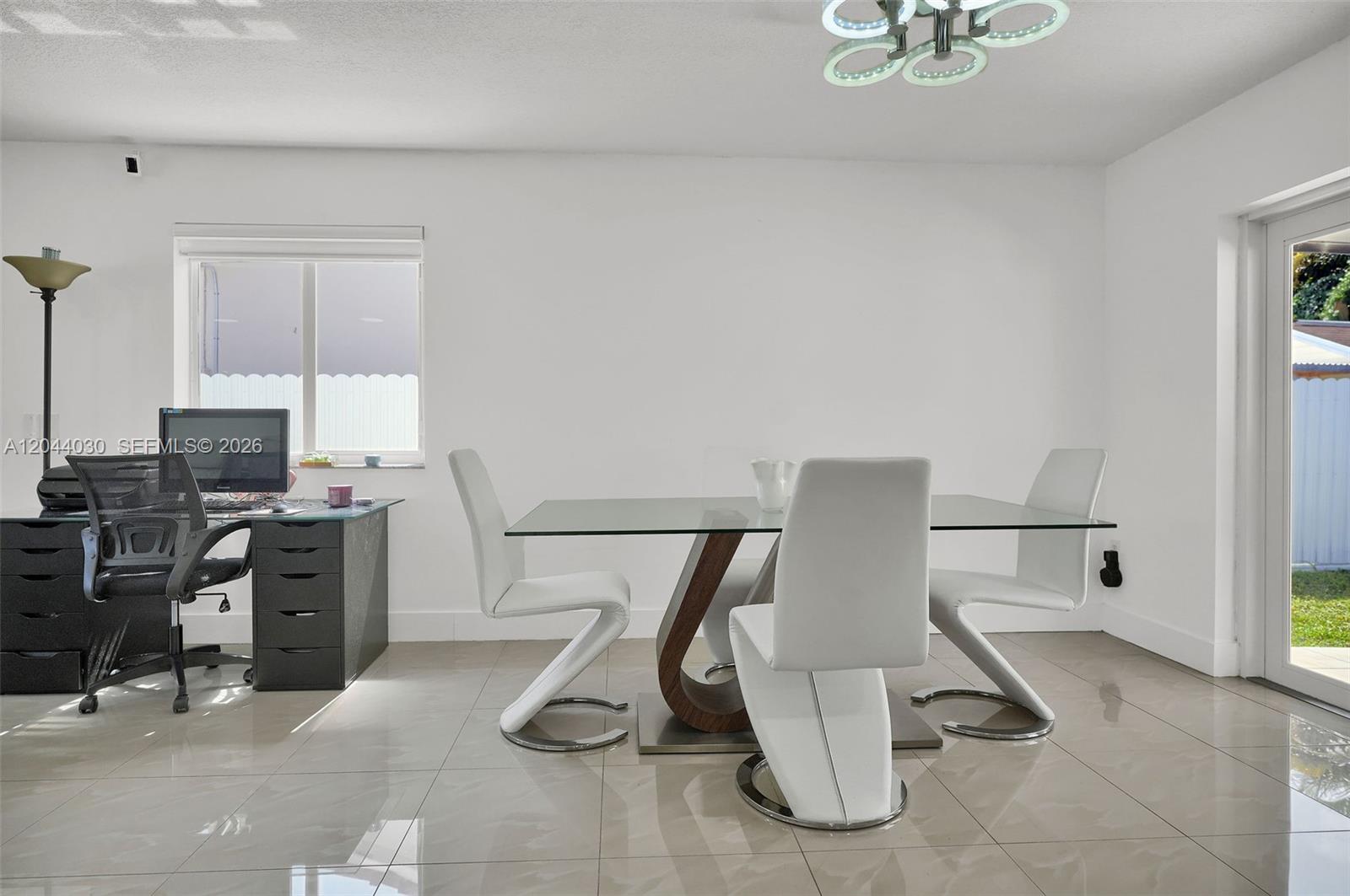 A dining room with a glass table, white chairs, a desk, and tile flooring — 12551 SW 223 ST, Miami FL 33170, MIAMI, FL