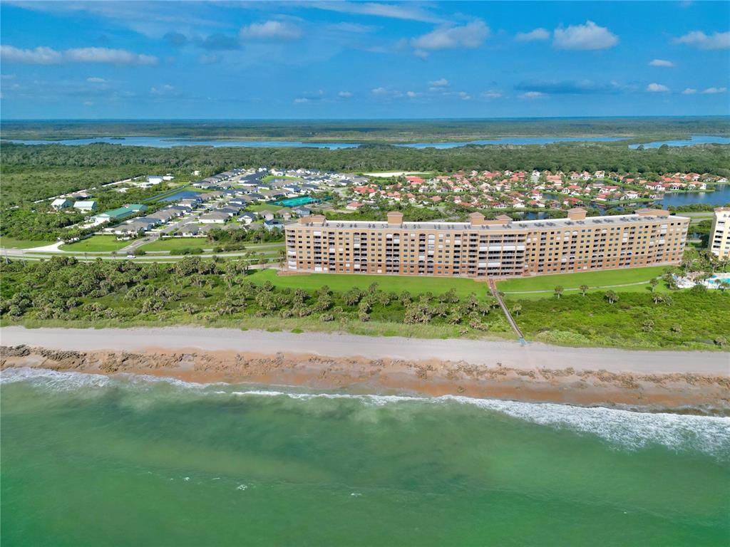 An aerial view shows a large beachfront condominium building situated near a residential neighborhood — 60 SURFVIEW DRIVE UNIT 421, PALM COAST, FL