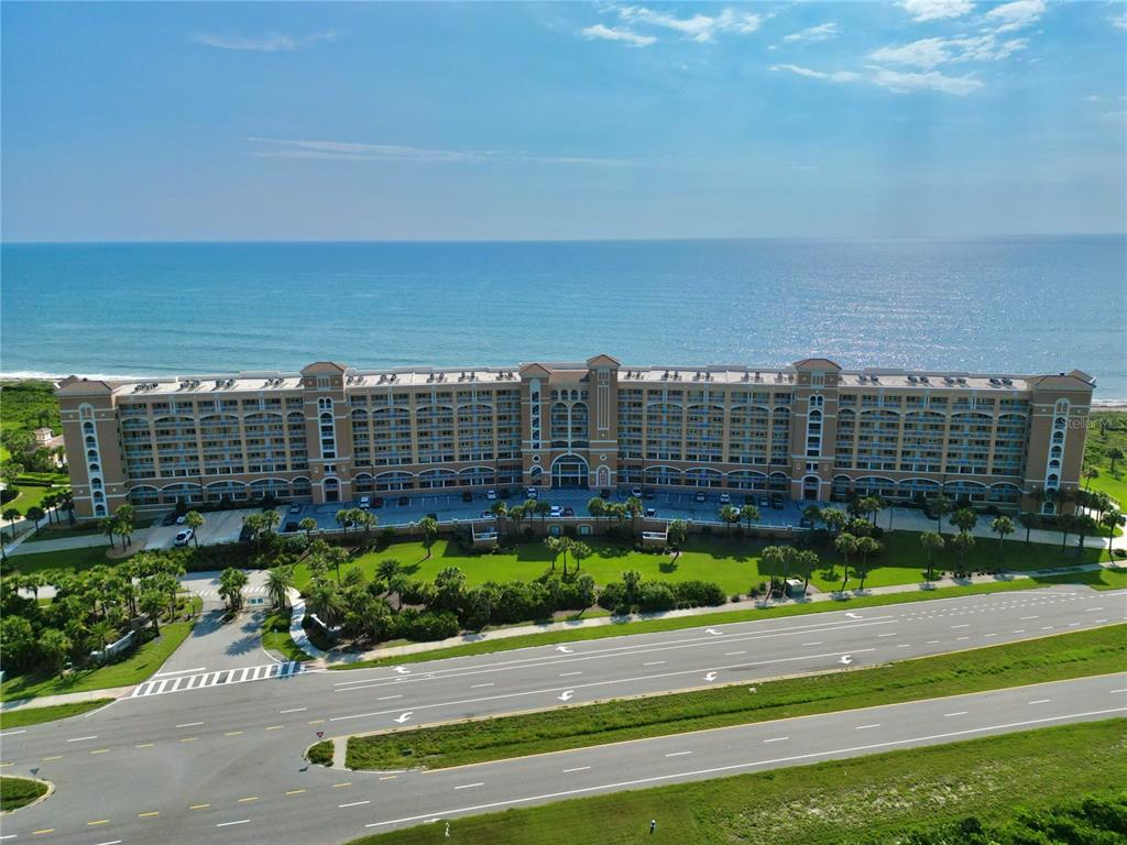 An aerial view of a large, multi-story beachfront resort building with a parking lot — 60 SURFVIEW DRIVE UNIT 421, PALM COAST, FL