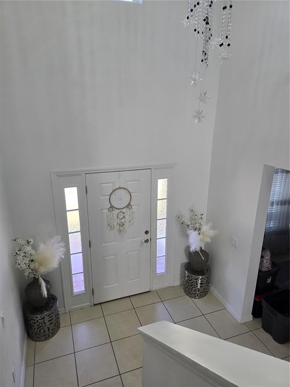 A high-ceilinged entryway features a white front door with sidelights, tile flooring, and decorative accents — 2259 WAUKEGAN DRIVE, KISSIMMEE, FL