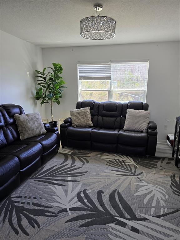 A living room features two dark leather sofas, a patterned rug, and a drum chandelier — 2259 WAUKEGAN DRIVE, KISSIMMEE, FL