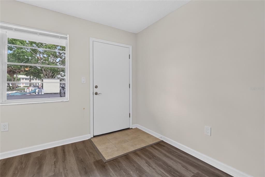 An interior view of an entryway with a white door, window, and wood-look flooring — 951 79TH AVENUE N UNIT 115, ST PETERSBURG, FL