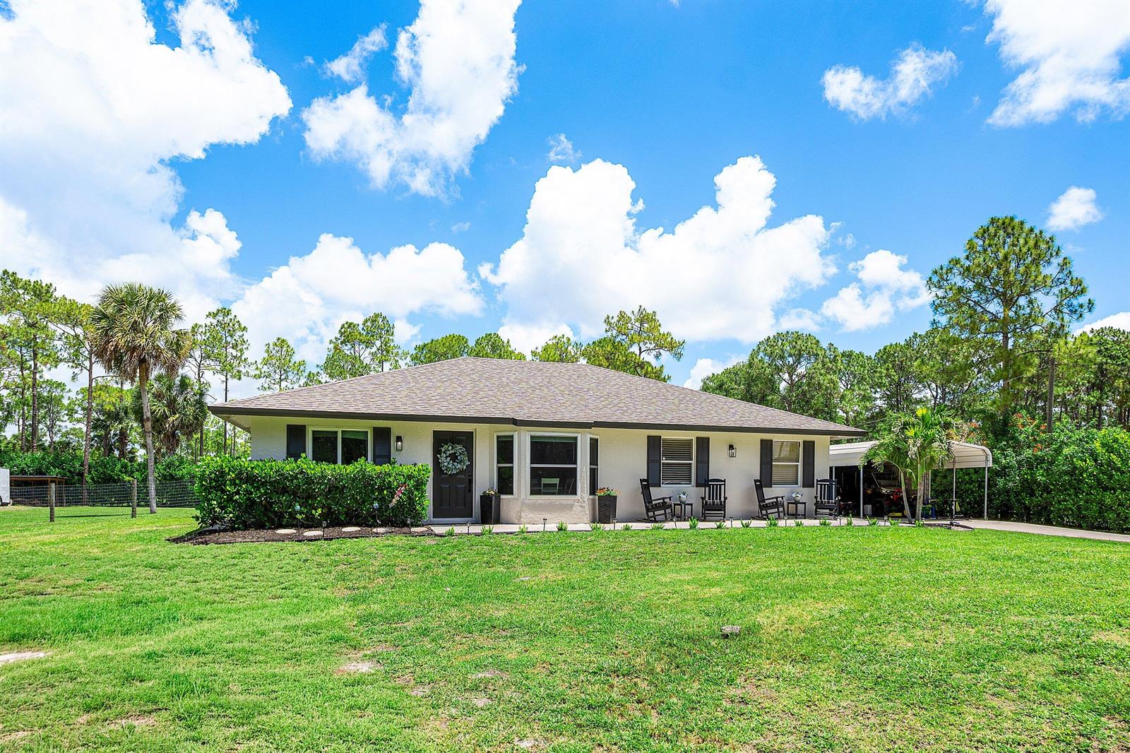 A single-story house with a white exterior, dark shutters, and a front lawn — 17105 N 70th St Street N, FL 33470, FL