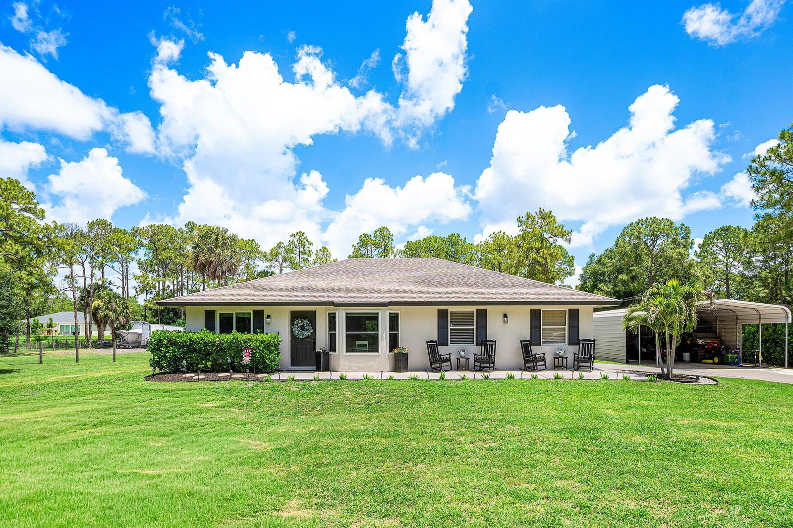 A single-story house with a light-colored exterior, dark shutters, and a large front lawn — 17105 N 70th St Street N, FL 33470, FL