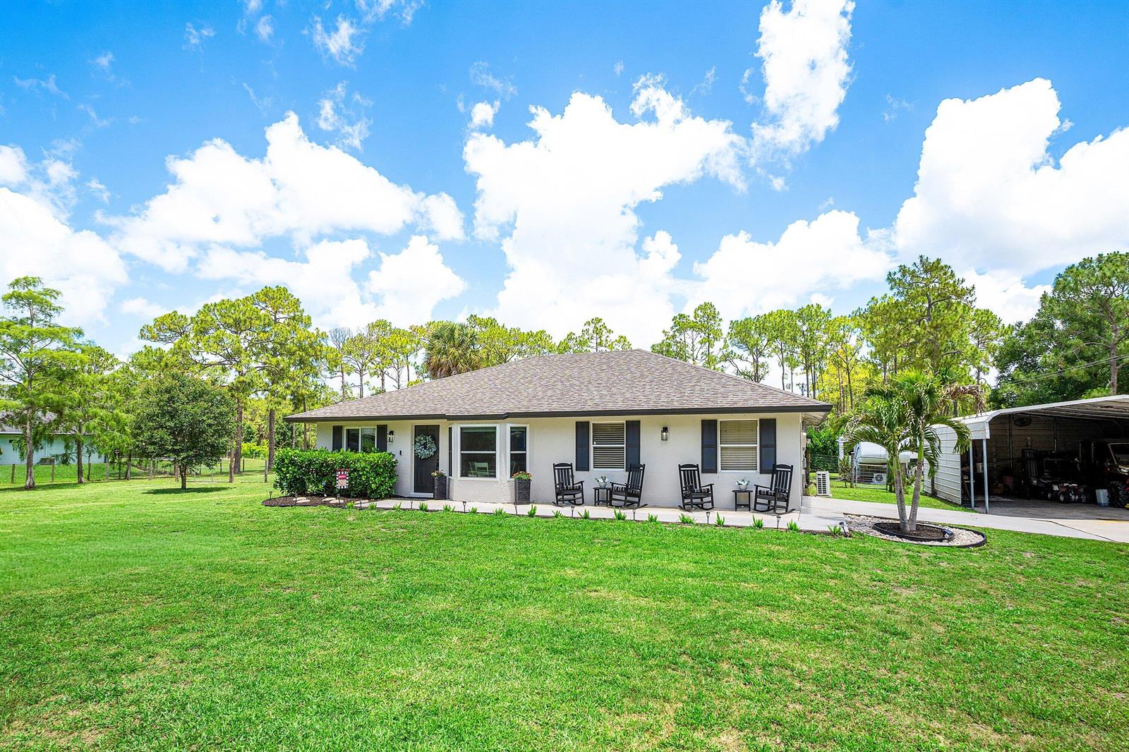 A single-story house with a light-colored exterior, dark shutters, and a front porch — 17105 N 70th St Street N, FL 33470, FL