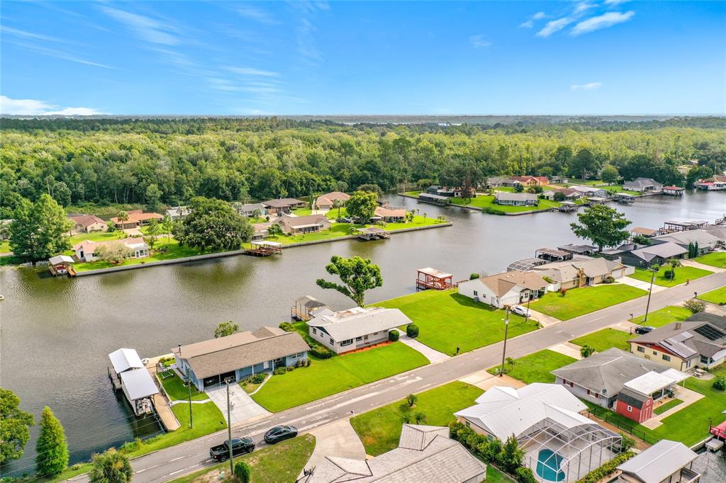An aerial view shows waterfront houses with private docks along a canal near trees — 13225 COUNTRY CLUB DRIVE, TAVARES, FL