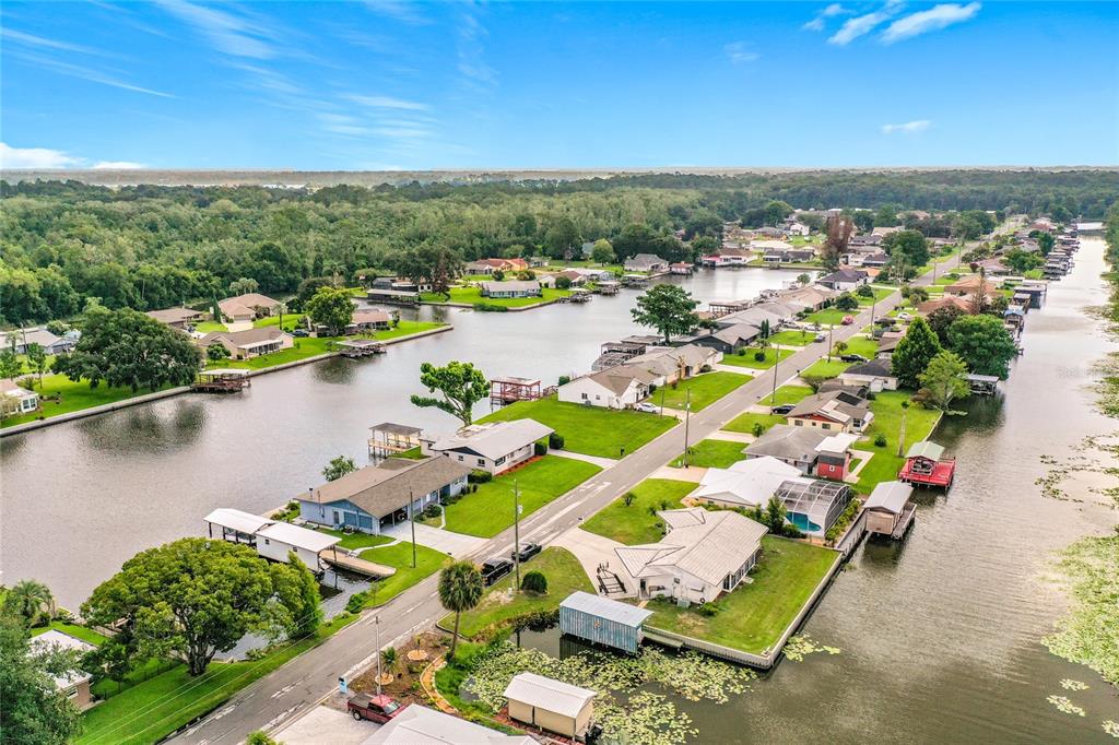 An aerial view shows houses along a canal with boat docks and lush green trees — 13225 COUNTRY CLUB DRIVE, TAVARES, FL