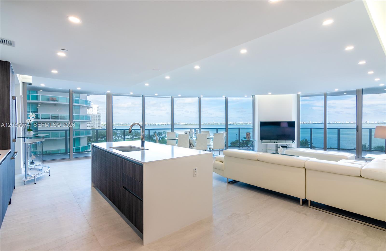 A modern open-concept kitchen and living area features floor-to-ceiling windows with panoramic water views — 488 NE 18th St # 615, Miami FL 33132, MIAMI, FL