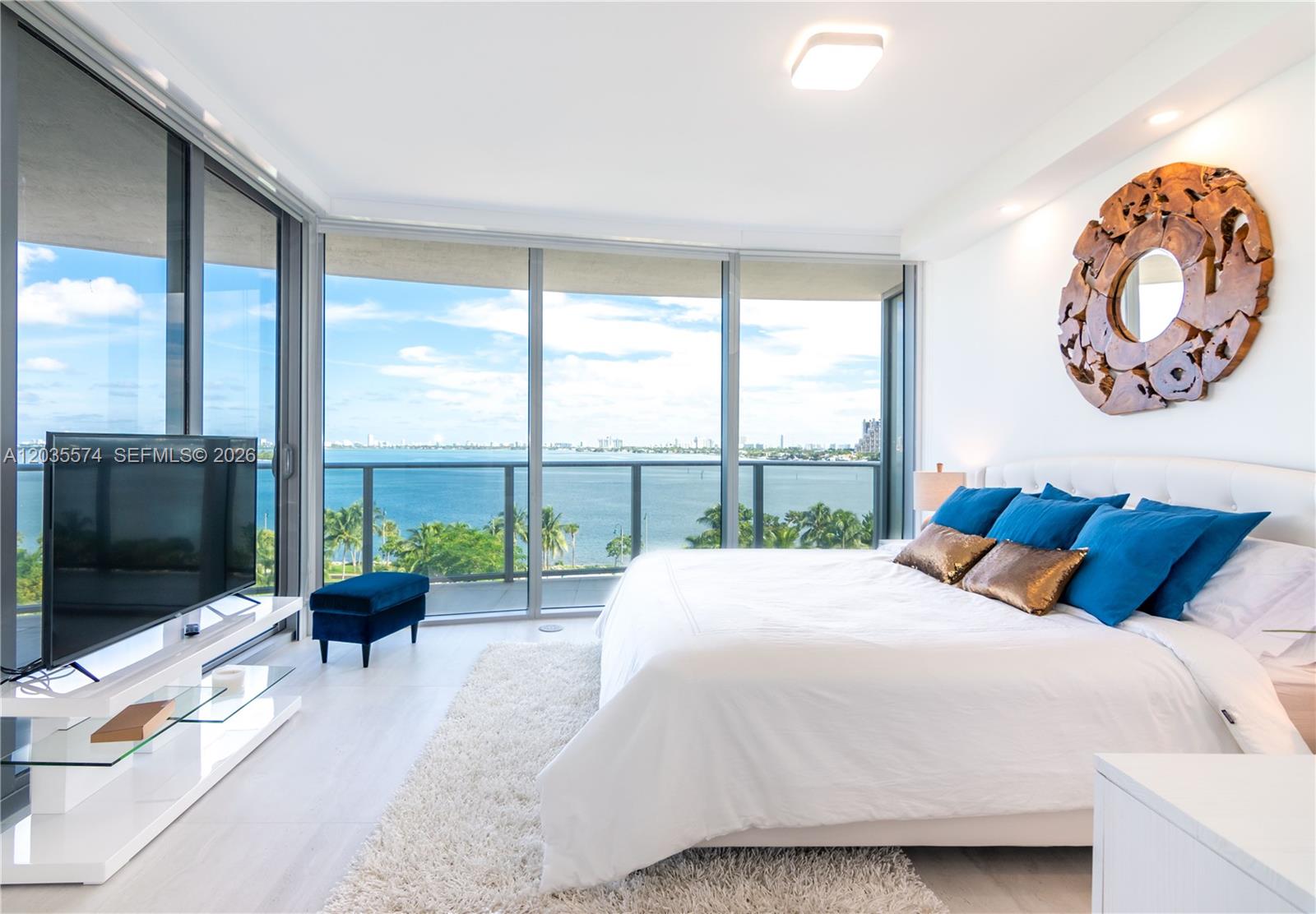 A bedroom features a bed, a television, and floor-to-ceiling windows overlooking the ocean — 488 NE 18th St # 615, Miami FL 33132, MIAMI, FL