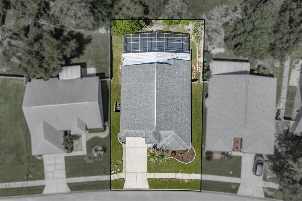 An aerial view shows a single-family home with a screened-in back patio and driveway — 5137 NEW BRITTANY LANE, ZEPHYRHILLS, FL