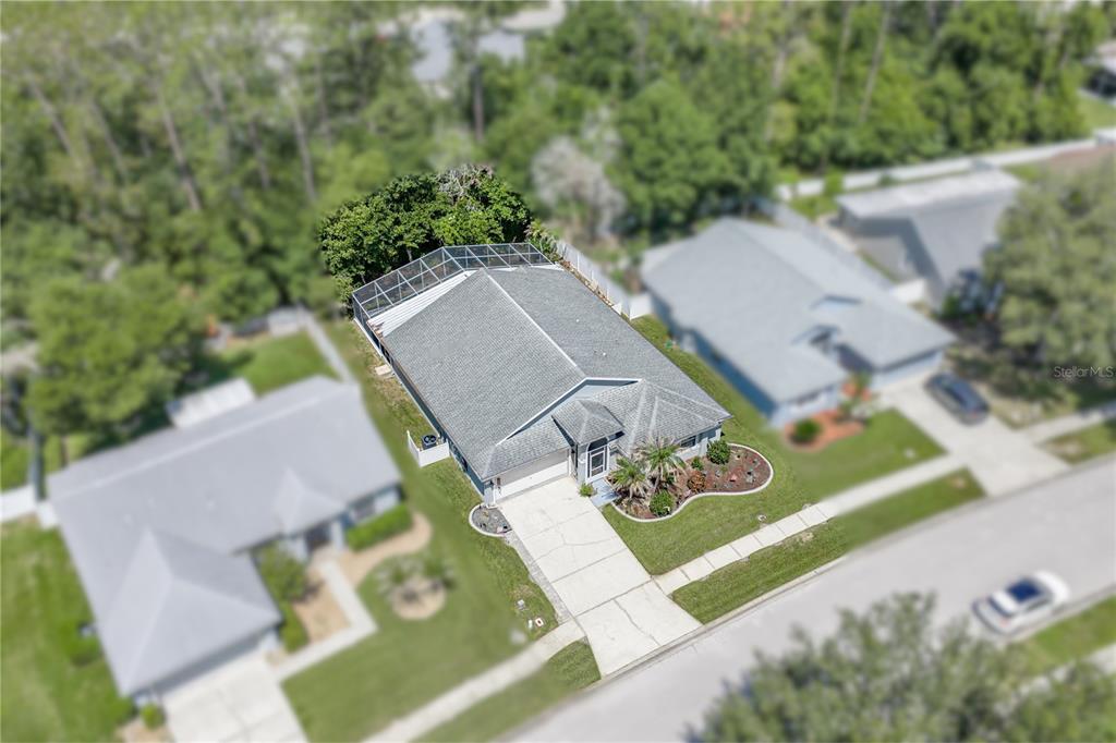 An aerial view shows a single-story house with a screened-in pool and concrete driveway — 5137 NEW BRITTANY LANE, ZEPHYRHILLS, FL