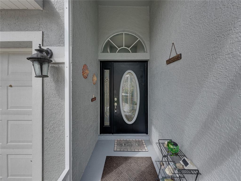 A front entryway features a black door with an oval glass insert and a transom window — 5137 NEW BRITTANY LANE, ZEPHYRHILLS, FL