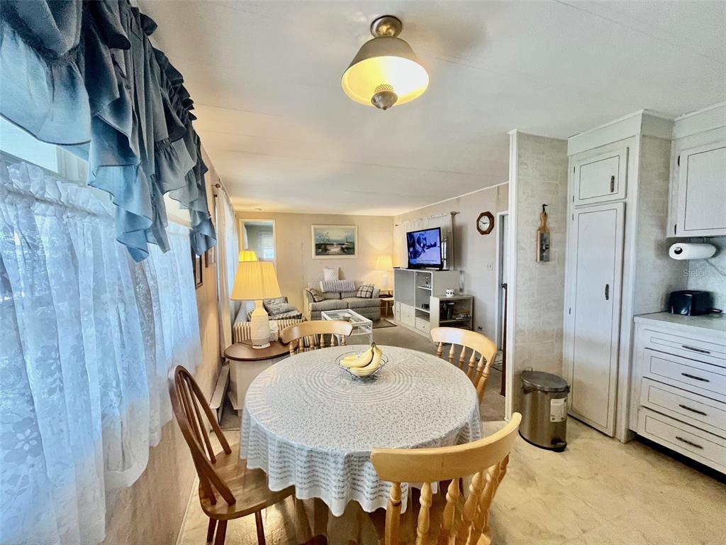 A dining area with a round table and chairs opens into a living room — 130 MELODY LANE, TARPON SPRINGS, FL