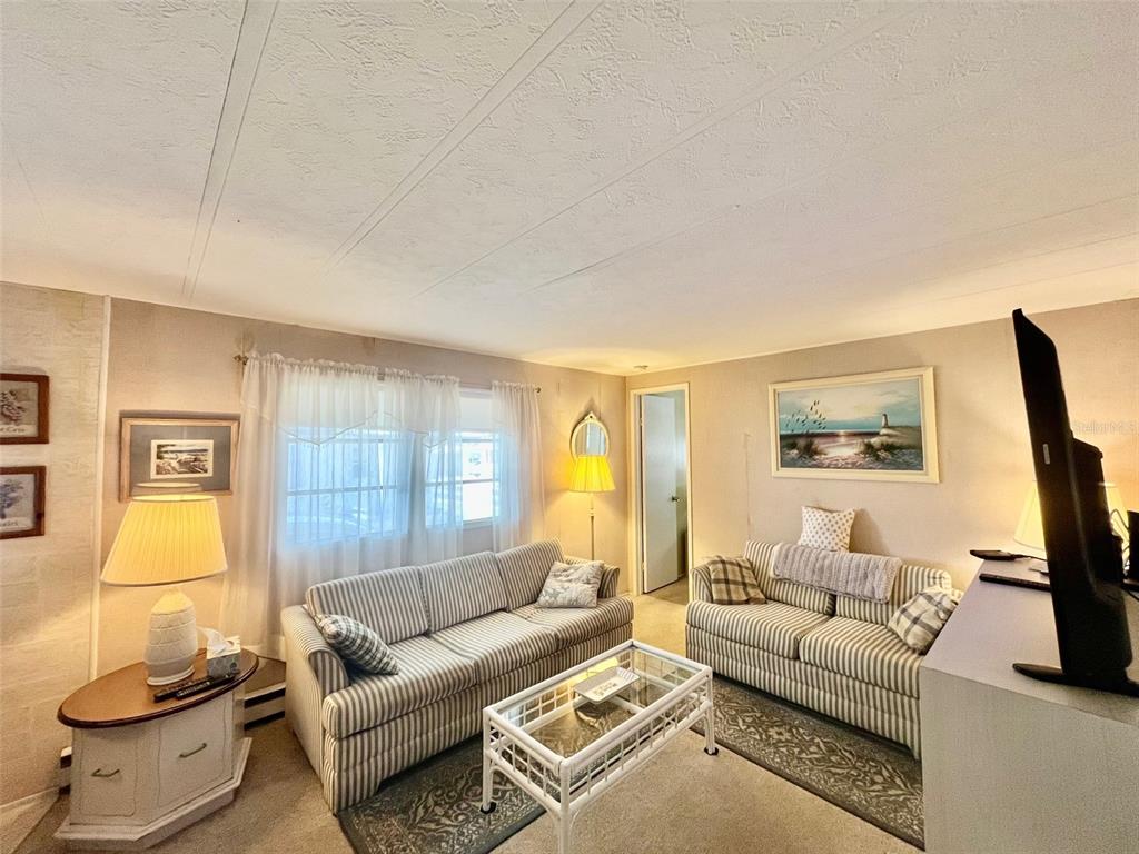 A living room features two striped sofas, a glass coffee table, and a floor lamp — 130 MELODY LANE, TARPON SPRINGS, FL