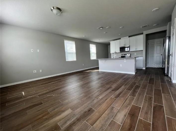 An open-concept kitchen and living area feature wood-look tile flooring and white cabinetry — 756 LEGACY DR, DAVENPORT, FL
