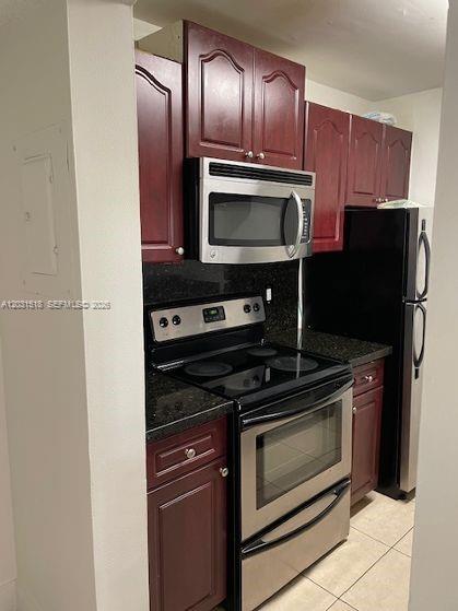 A kitchen features dark wood cabinets, stainless steel appliances, and black granite countertops — DORAL, FL