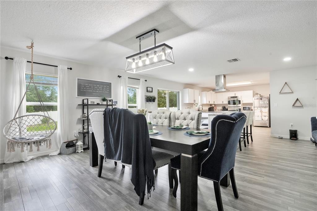 A dining area with a dark table, upholstered chairs, a hanging chair, and an open kitchen — 301 SALMON WAY, KISSIMMEE, FL