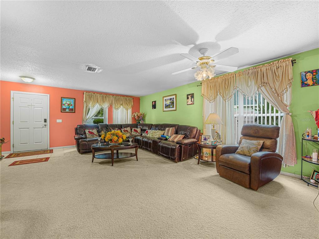 A living room features a large brown sectional sofa, a recliner, and light green walls — 7448 HUNTERS GREENE CIRCLE, LAKELAND, FL