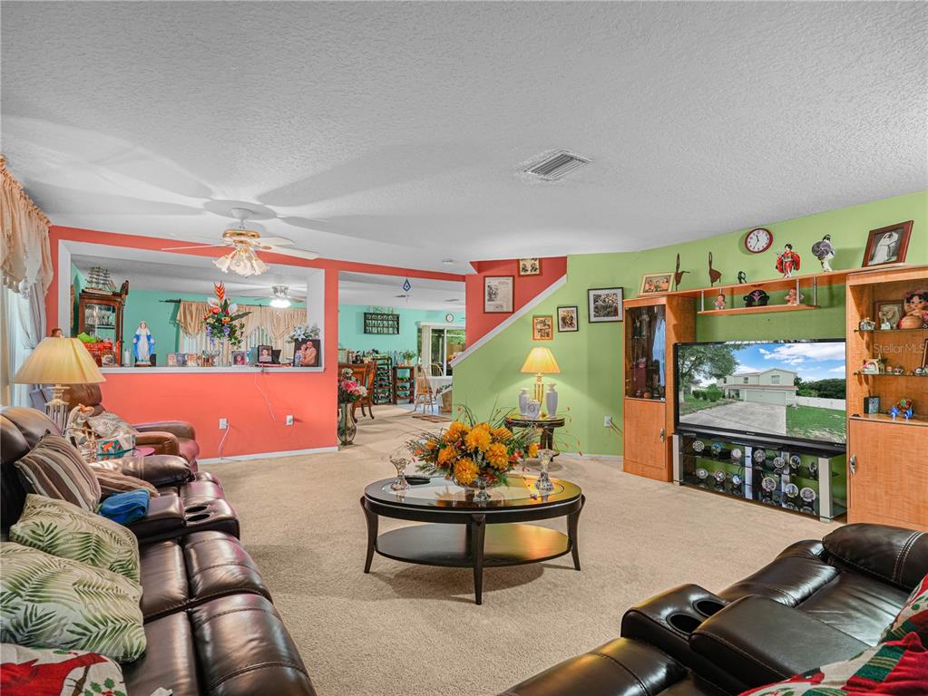 A living room features a brown leather sofa, a coffee table, and colorful accent walls — 7448 HUNTERS GREENE CIRCLE, LAKELAND, FL