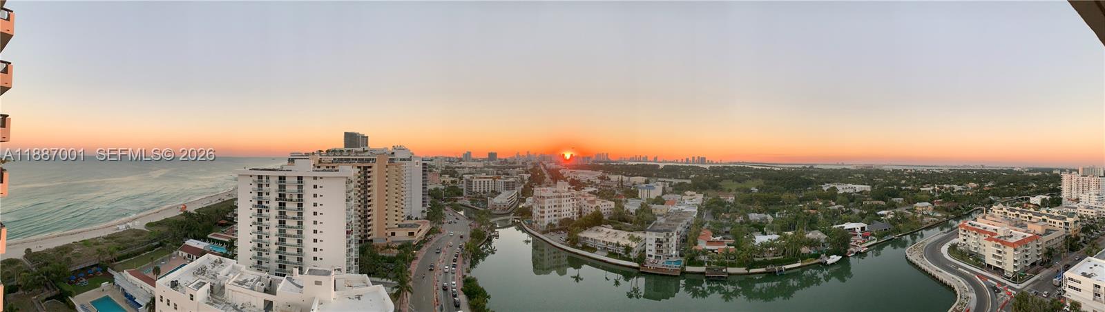 An elevated panoramic view shows a coastal city skyline at sunset with a canal below — 2555 Collins Ave # 2112, Miami Beach FL 33140, MIAMI BEACH, FL