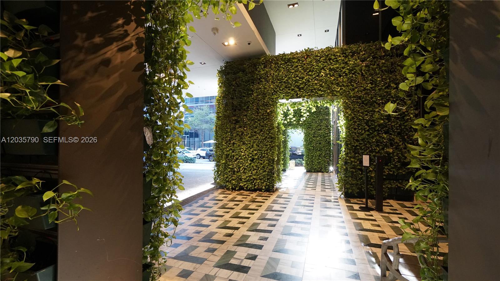 A covered walkway features walls covered in greenery and a patterned tile floor — 801 S Miami Ave # 2506, Miami FL 33130, MIAMI, FL