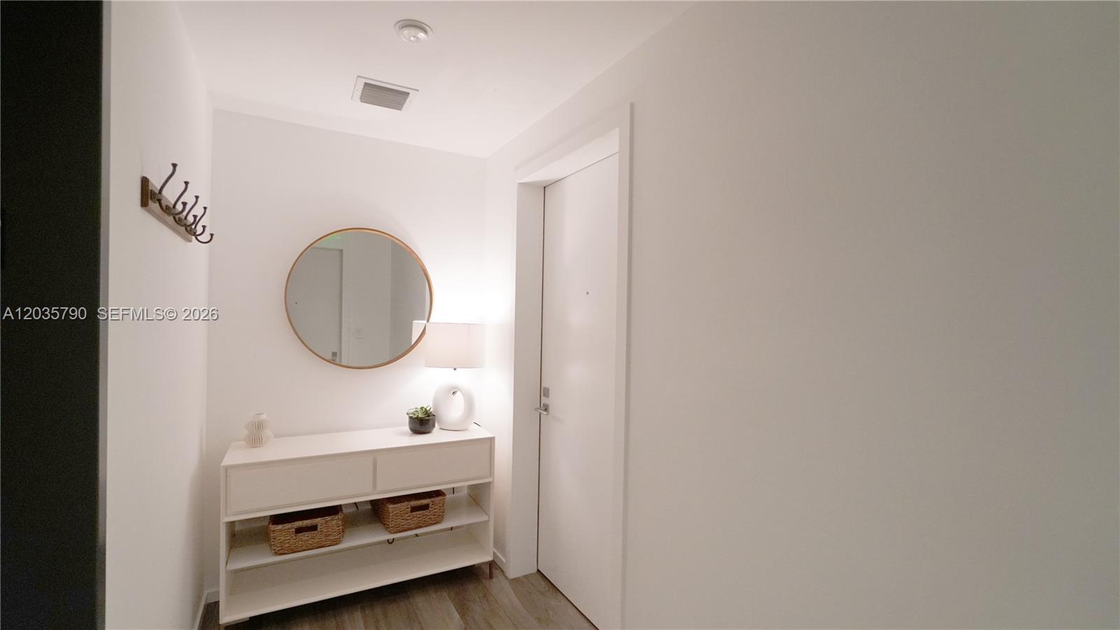 A white entryway features a console table, a round mirror, and a wall-mounted coat rack — 801 S Miami Ave # 2506, Miami FL 33130, MIAMI, FL