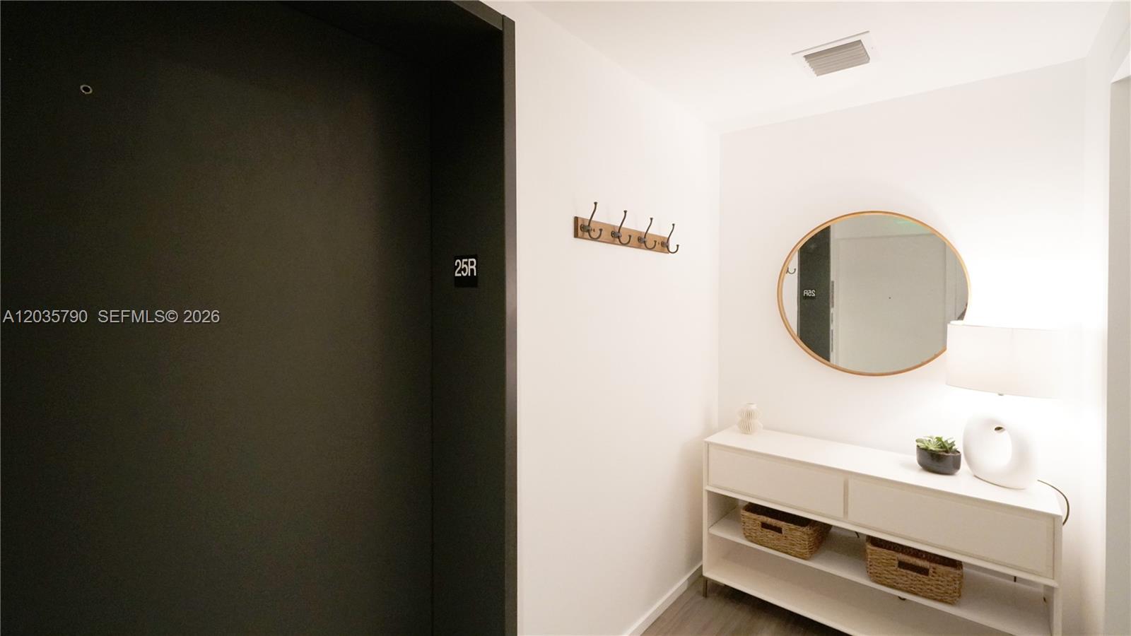 An entryway features a dark door, a wall-mounted coat rack, and a white console table — 801 S Miami Ave # 2506, Miami FL 33130, MIAMI, FL